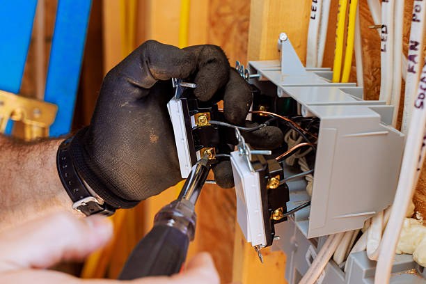 Electricista con guantes instalando interruptores