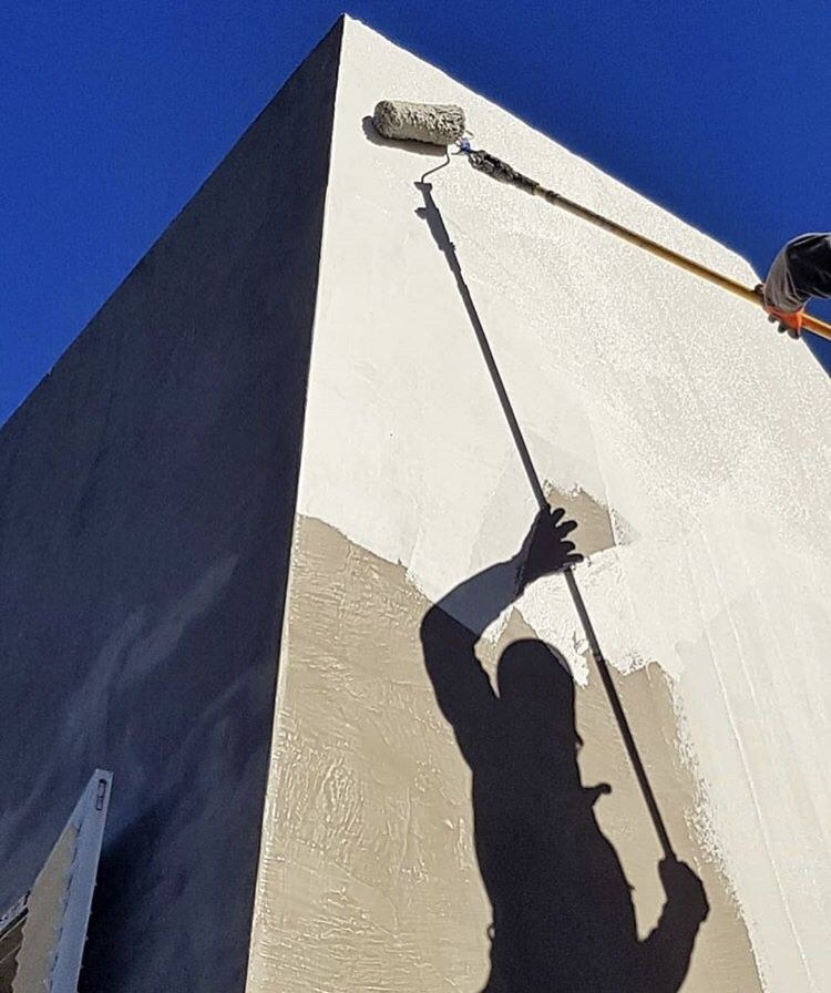 Pintor aplicando pintura en la esquina de una fachada